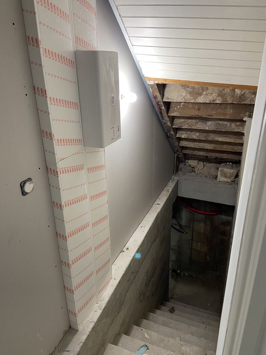 Tableau électrique neuf installé dans une cage d'escalier menant à la cave